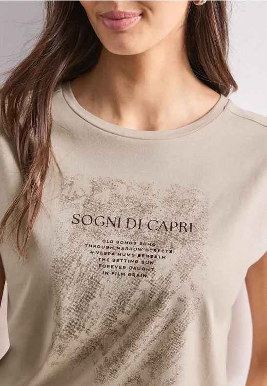 Beige T-Shirt mit Schriftzug 'Sogni di Capri' und Pinselstrich-Print, getragen von einer Frau.