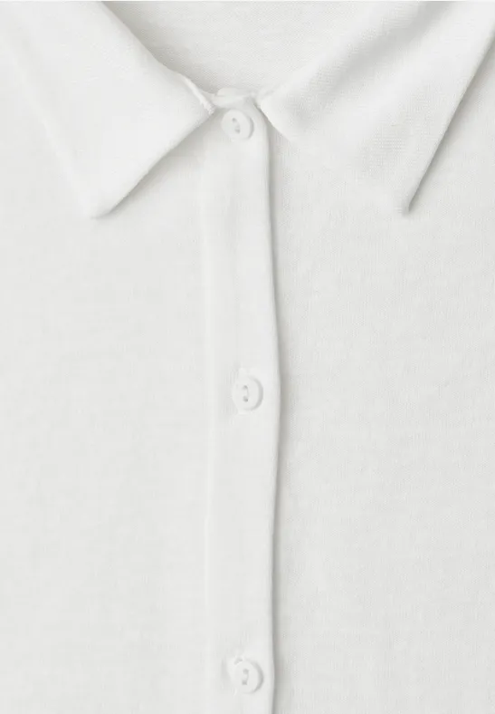 Close-up van een wit poloshirt met kraag en drie knopen.