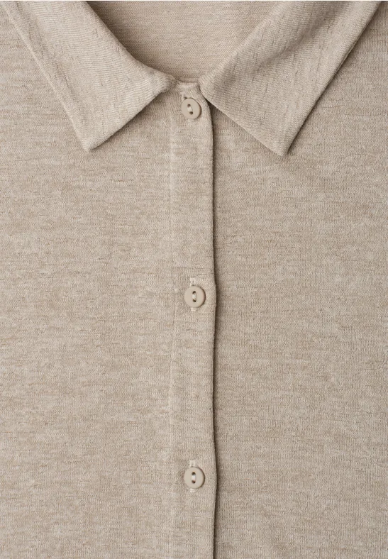 Nahaufnahme eines beigen Strickcardigans mit Hemdkragen und Knopfleiste.