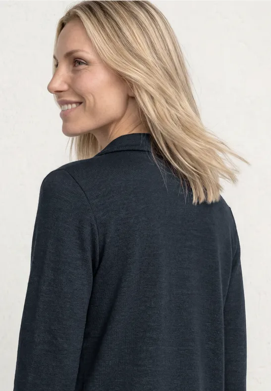 Frau in dunkelgrauem Blazer, Rückenansicht, helle Haare vor weißem Hintergrund.