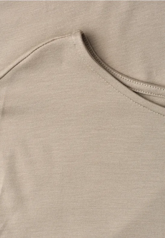 Nahaufnahme eines beigen T-Shirt-Ausschnitts aus weichem Stoff.
