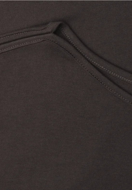 Gros plan sur la couture et la poche d’un sweat à capuche marron.