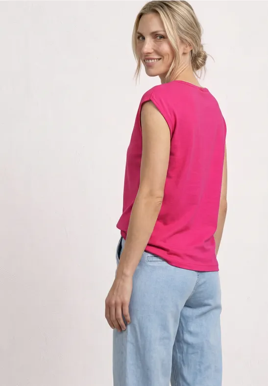 Femme vue de dos portant un débardeur rose et un jean bleu clair sur fond neutre.