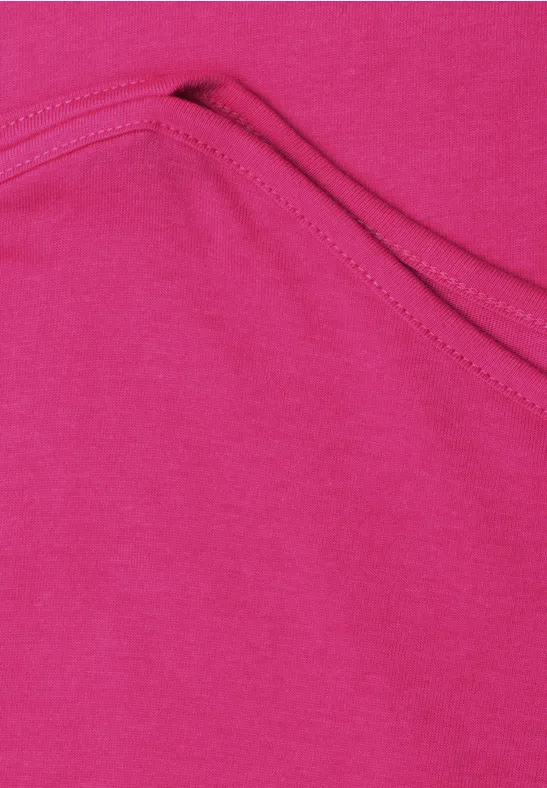 Gros plan sur un tissu rose vif avec poche cousue et surpiqûre apparente.