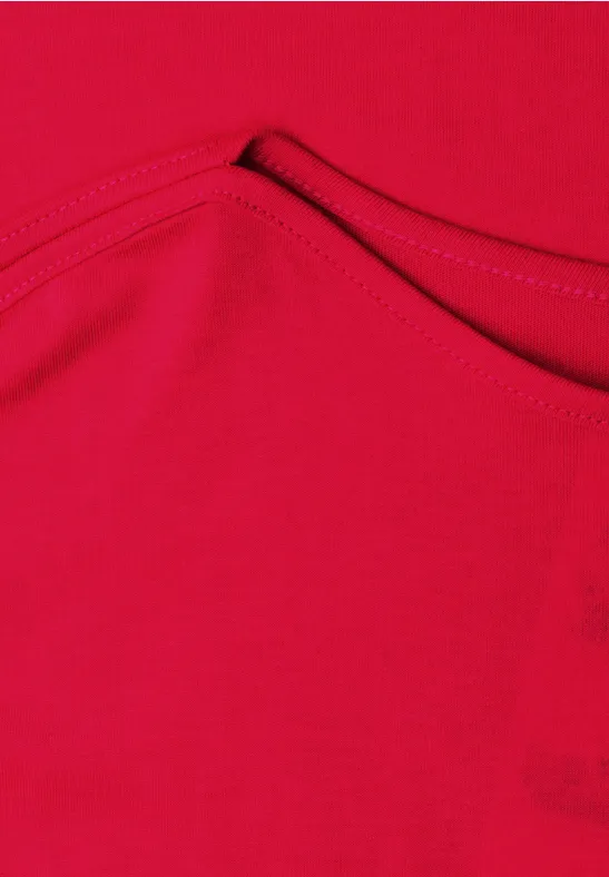 Rotes Kleidungsstück aus Stoff mit sichtbarer Naht und kleiner Tasche.