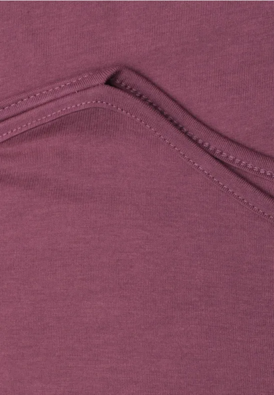 Gros plan sur un tissu violet bordeaux avec couture et plis de poche.