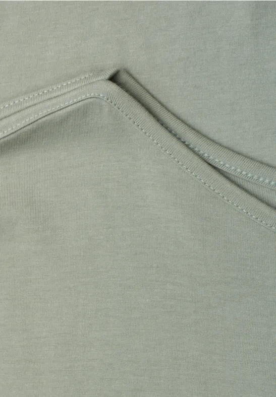 Close-up van grijsgroen textiel met decoratieve stiksels.
