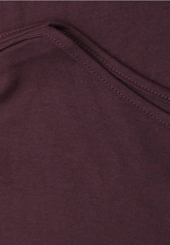 Close-up van een bordeauxrode stoffen zak met zichtbare naad.