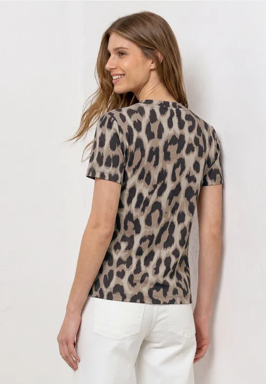 Vrouw van achteren in een kort mouwtjes t-shirt met luipaardprint en een witte broek.