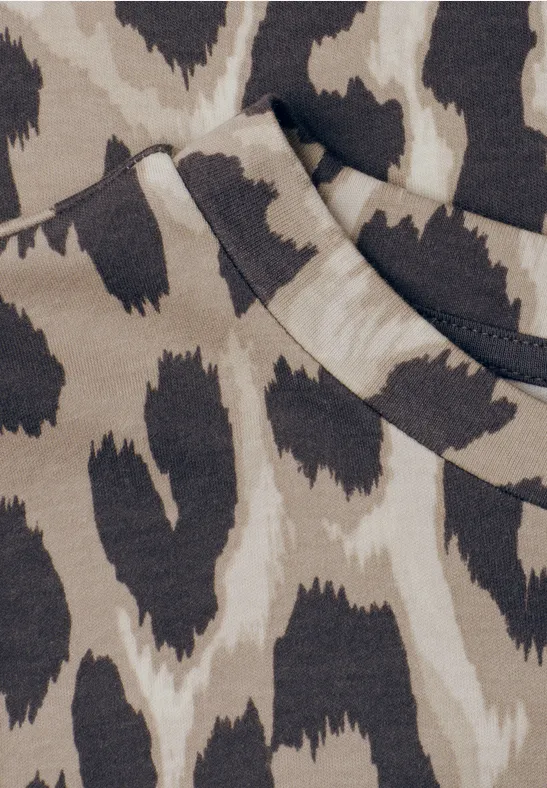 Close-up van een beige kledingstuk met bruin-zwarte luipaardprint en een zakopening
