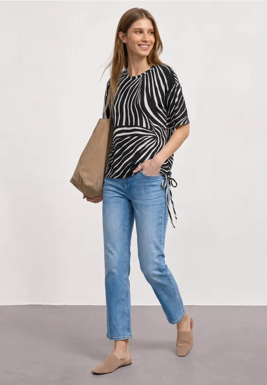 Femme en top zébré, jean bleu, mocassins beiges et grand sac