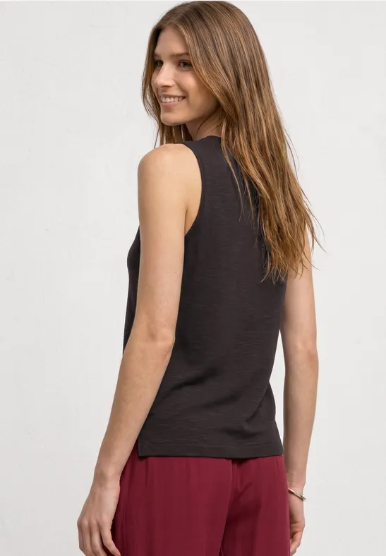 Frau von hinten in schwarzem Tanktop und roter Hose vor hellem Hintergrund.