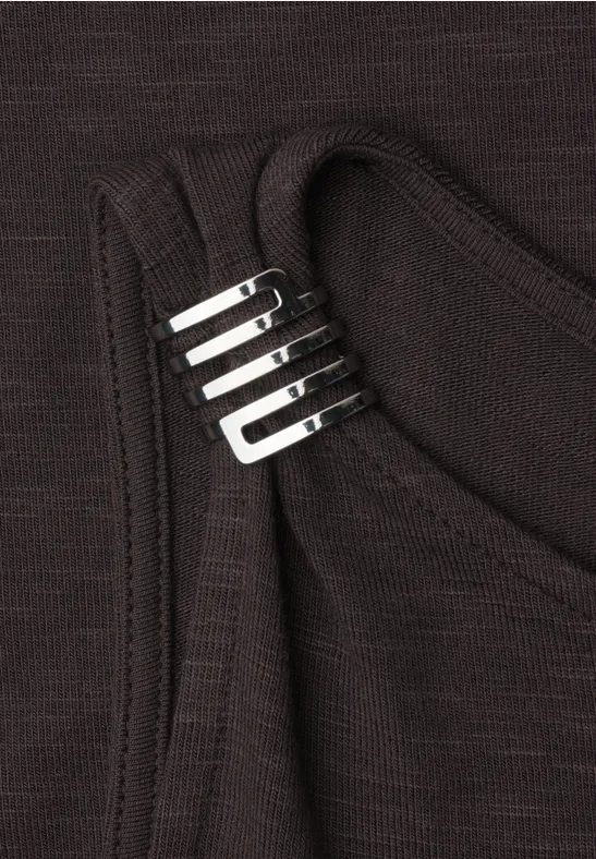 Schwarzes Tanktop mit silbernen Metallbeschlägen am Träger.