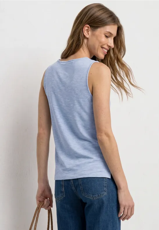 Frau von hinten in hellblauem ärmellosem Top und Jeans, hält eine braune Tasche.