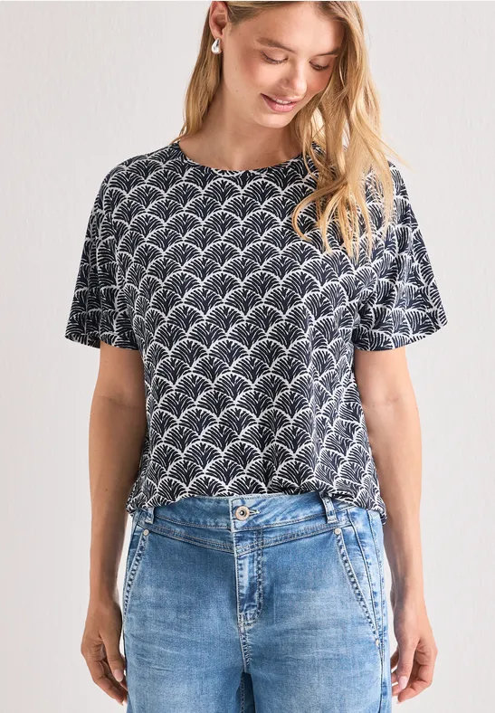 Frau trägt dunkelblaues T-Shirt mit weißem Wellenmuster und blaue Jeans