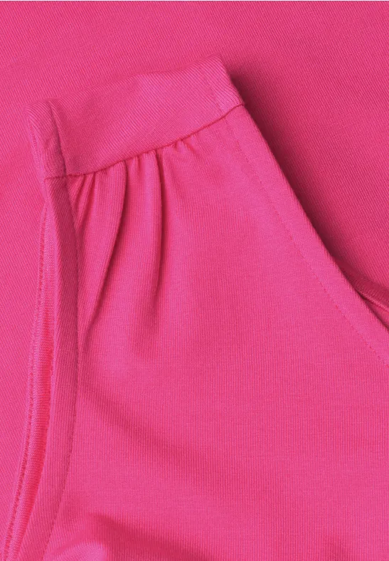 Gros plan sur un pantalon rose vif avec ceinture élastique et poche latérale.