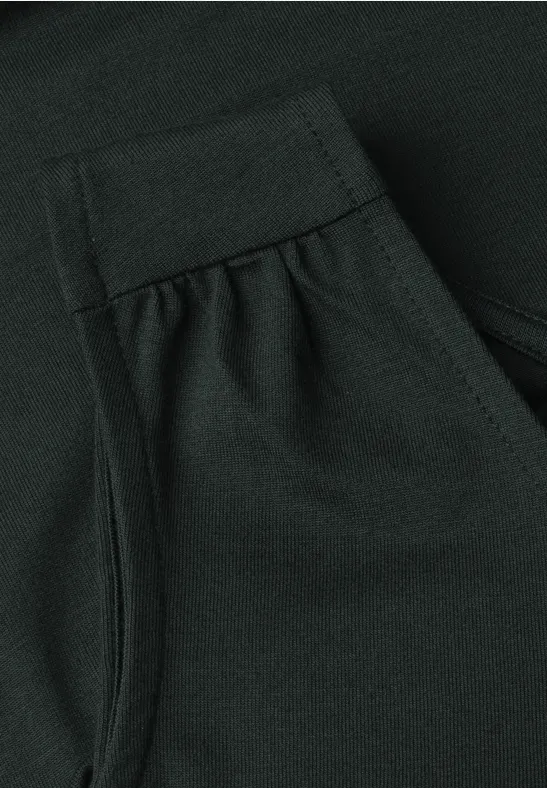 Gros plan d'un vêtement vert foncé en tissu avec couture apparente, pli et petite poche