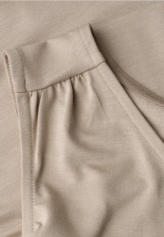 Gros plan d'un vêtement beige avec poche et texture de tissu fine.