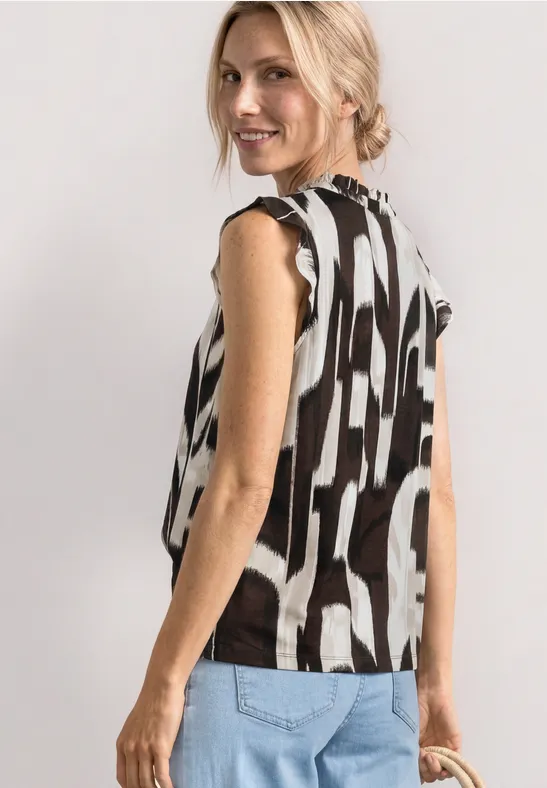 Femme de profil portant un top sans manches à motifs noir et blanc et un jean clair