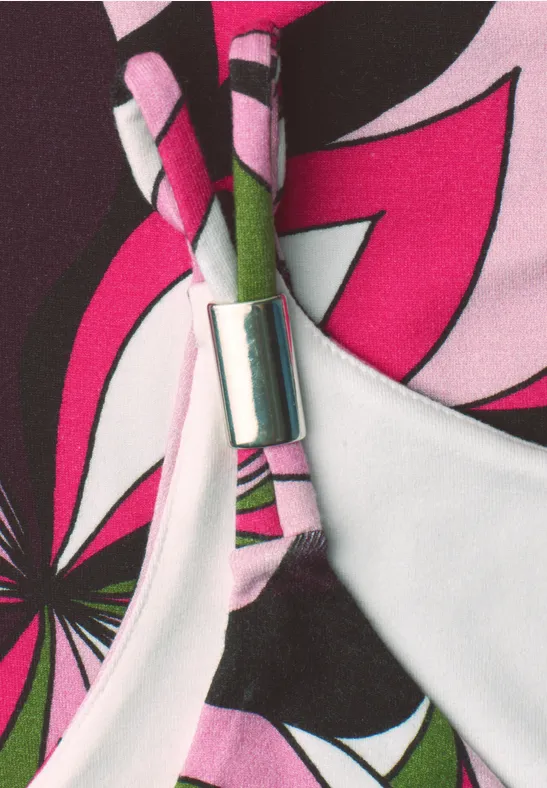 Detailaufnahme eines bunten Bikini-Oberteils mit pink-schwarzem Blumenmuster und silberner Klammer.