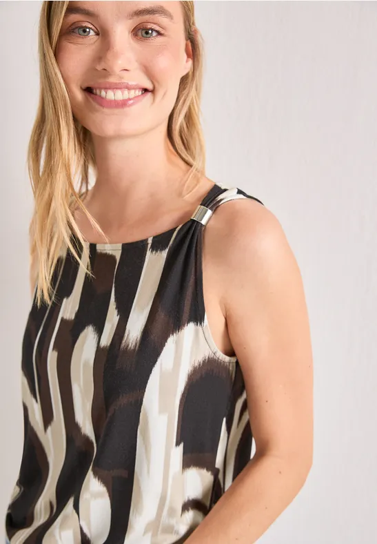 Femme souriante en robe sans manches noir et blanc, devant un fond clair