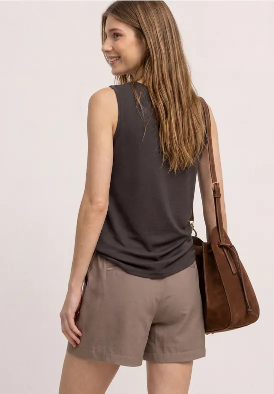 Femme de dos portant un haut sans manches noir, un short marron et un sac assorti.