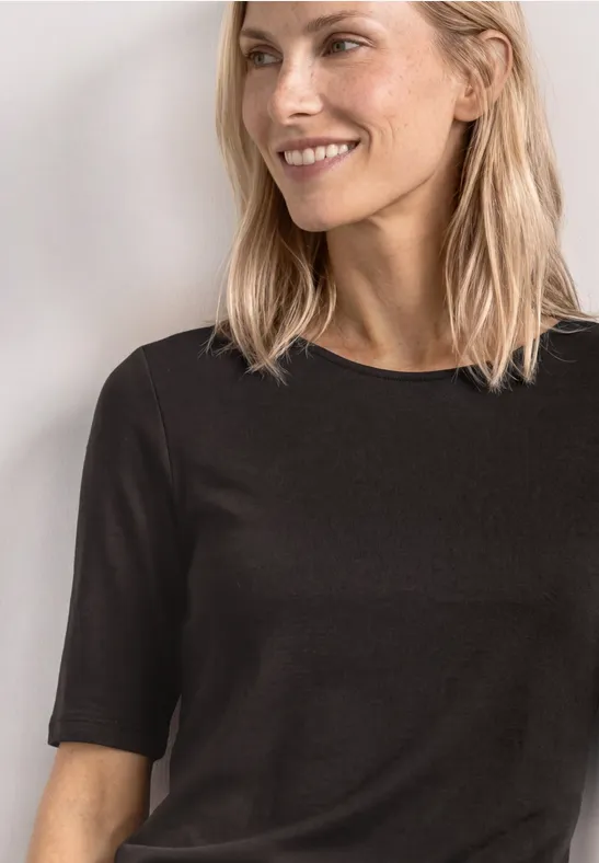 Vrouw met blond haar draagt een simpel zwart T-shirt met korte mouwen, vooraanzicht tot aan de borst.