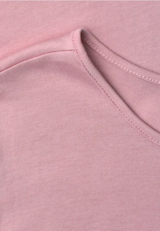 Close-up van een roze T-shirt met ronde halslijn.