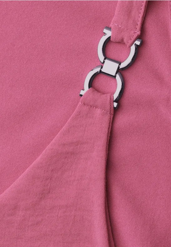Nahaufnahme eines rosa Stoffes mit silberfarbenem Riemenring an einem Träger.
