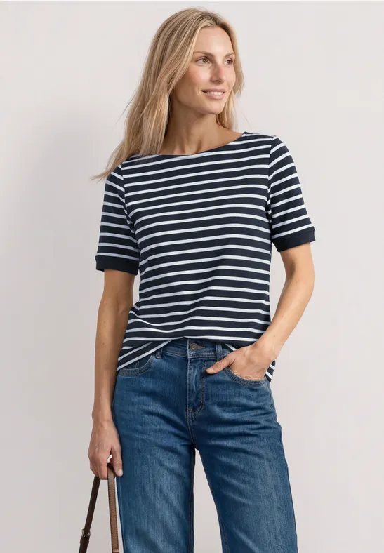 Frau mit blau-weiß gestreiftem T-Shirt, blonden Haaren, Jeans und Tasche.