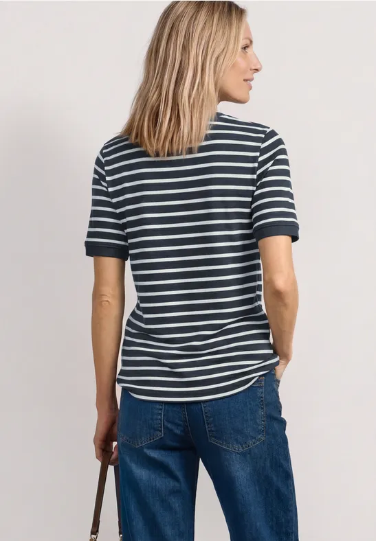Frau von hinten in gestreiftem T-Shirt und Jeans, die eine Tasche in der rechten Hand hält.