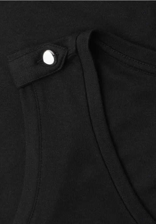 Detailaufnahme eines schwarzen Kleidungsstücks mit silberner Druckknopfleiste.