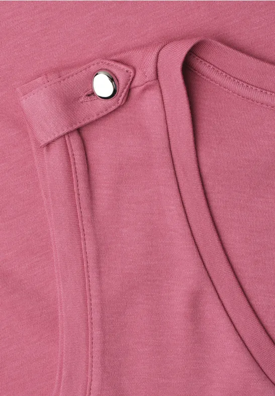 Nahaufnahme eines rosa ärmellosen Oberteils mit silbernem Druckknopf an der Schulter.