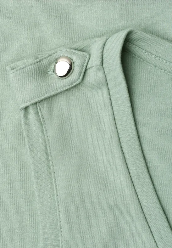 Gros plan sur un tissu vert menthe avec sangle, couture et bouton-pression argenté.