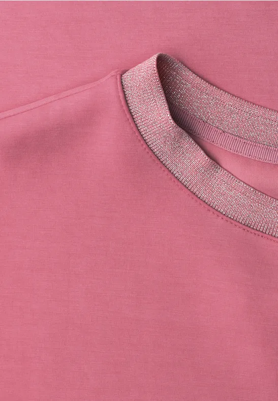 Nahaufnahme eines rosa Sweatshirts mit Rundhalsausschnitt und feinen Nahtdetails.