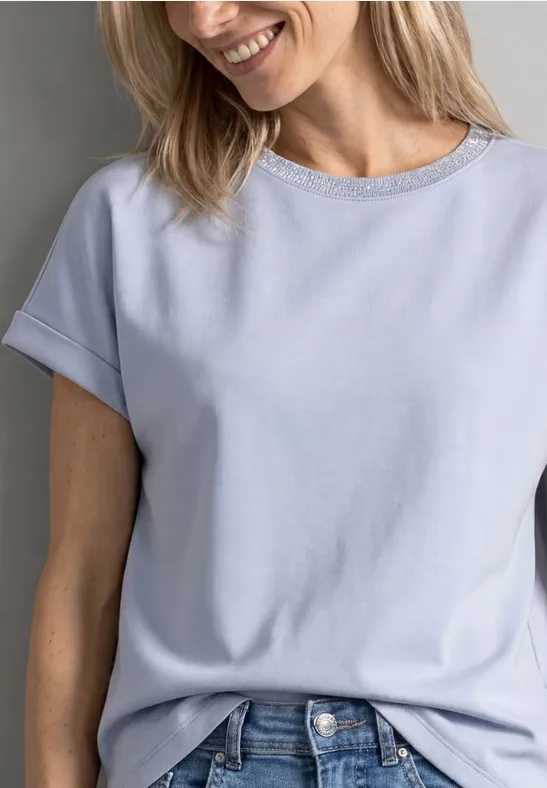 Eine lächelnde Frau in einem hellblauen T-Shirt und Jeans.