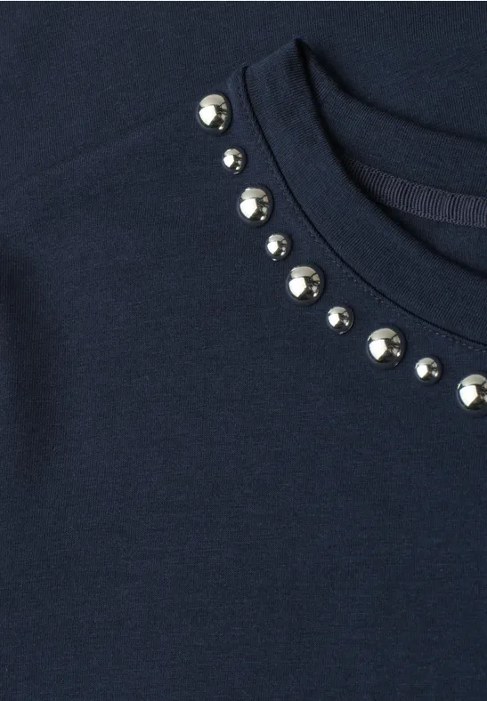 Dunkelblaues Shirt mit runder Halsöffnung, verziert mit silbernen Zierknöpfen.