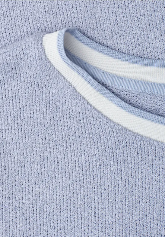 Close-up van een lichtblauw gebreid shirt met een witte, ronde halsafwerking.