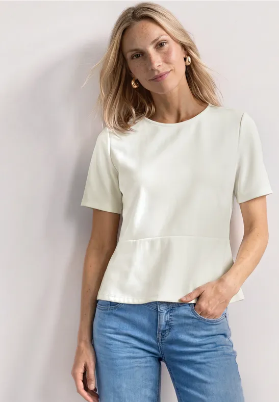Vrouw met wit kort T-shirt en blauwe spijkerbroek tegen neutrale achtergrond.