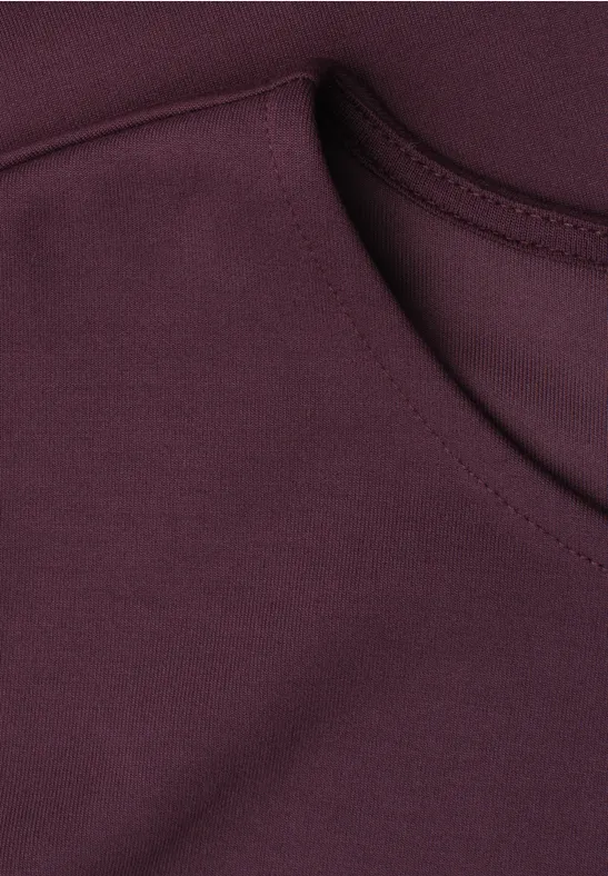 Nahaufnahme des Halsausschnitts eines bordeauxfarbenen Shirts.
