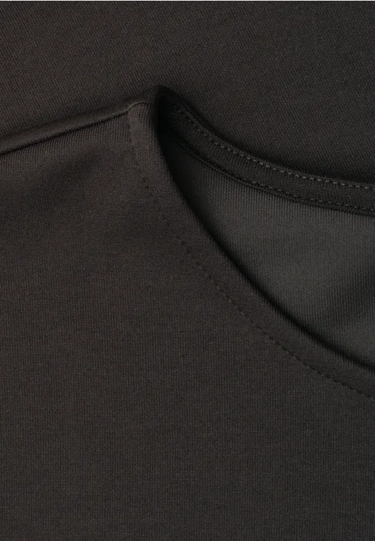 Close-up van een zwart shirt met ronde hals en fijne stiksels.