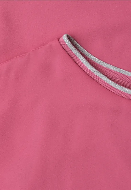 Nahaufnahme eines pinken Sportshirts mit grauem Rundhalsausschnitt.