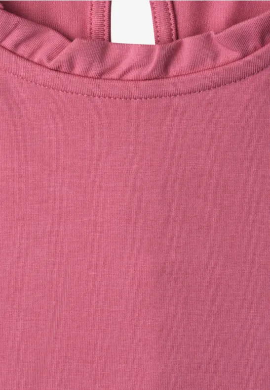 Nahaufnahme eines rosa Oberteils mit Rüschen am Halsausschnitt.