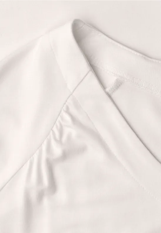 Nahaufnahme eines weißen V-Ausschnitt-Shirts mit feinem Stoff und sichtbaren Nähten.
