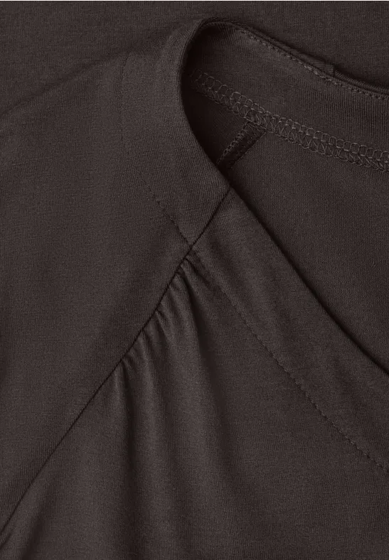 Close-up van een donker, glad textiel met zichtbare naad en lichte plooien.