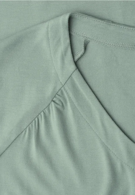 Nahaufnahme eines mintgrünen T-Shirts mit V-Ausschnitt und sichtbarer Naht.