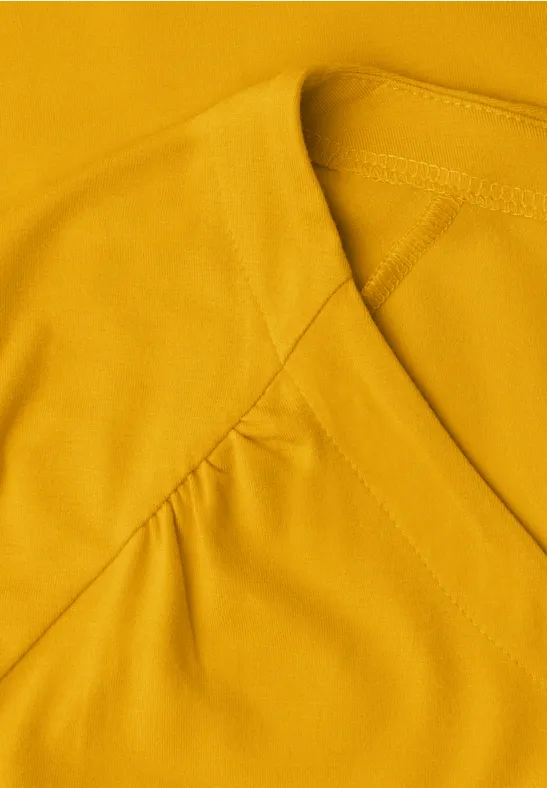 Haut jaune à encolure en V avec fronces discrètes aux épaules.