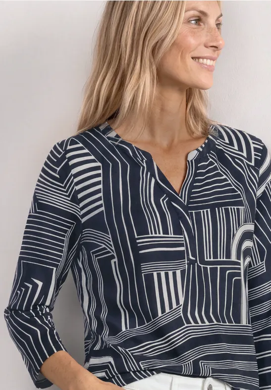 Frau in schwarz-weißer, geometrisch gemusterter Bluse, Oberkörper im Bild