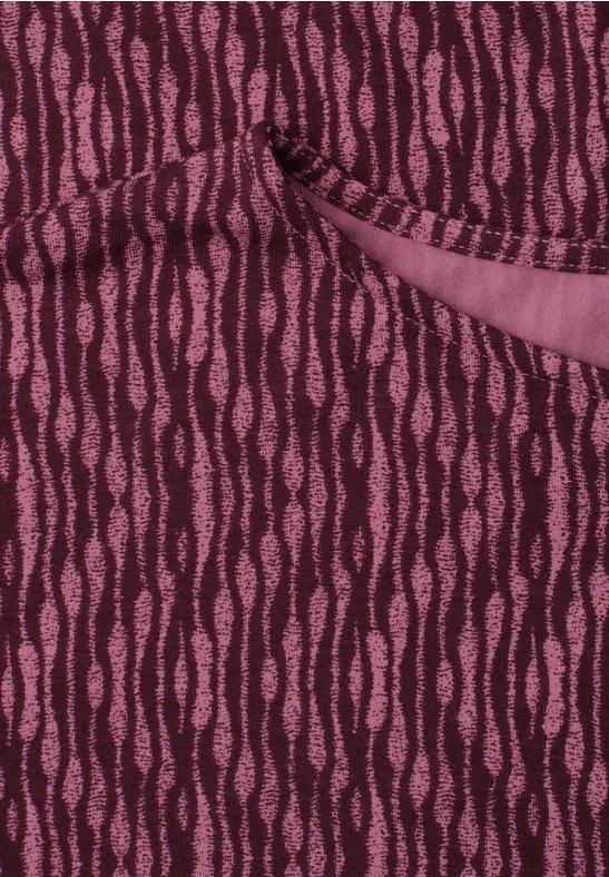 Nahaufnahme eines burgunderfarbenen Strickstoffs mit rosafarbenen, wellenförmigen Streifen und einer Tasche.
