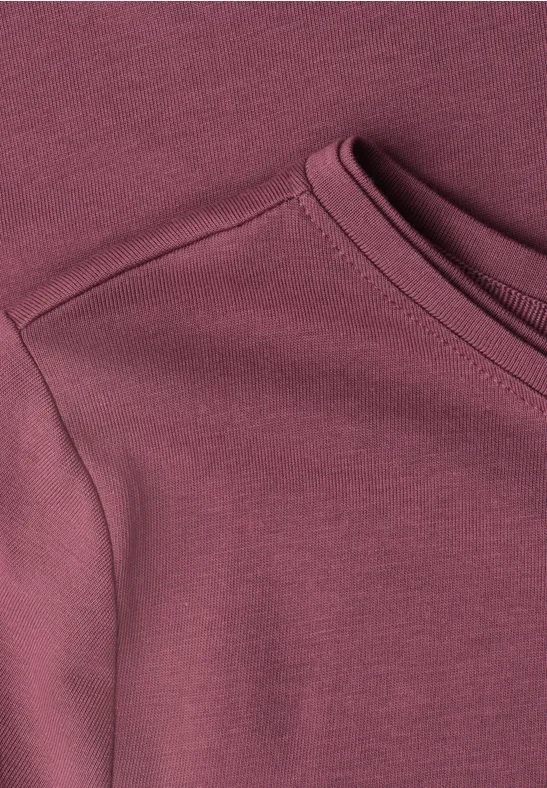 Close-up van de halslijn van een bordeauxrood T-shirt van zachte stof